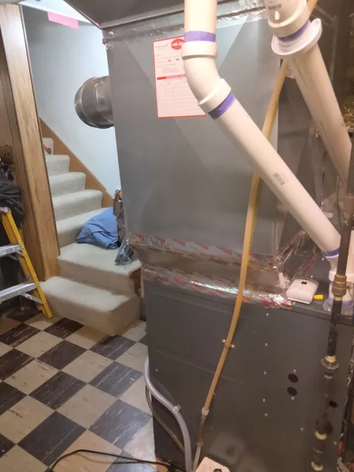 High-efficiency furnace and air handler installed next to a basement stairway