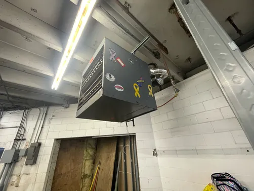 Commercial gas unit heater suspended from a warehouse ceiling by Midland Heating & Cooling