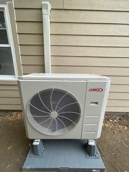 Lennox mini-split heat-pump outdoor unit on composite pads beside a home