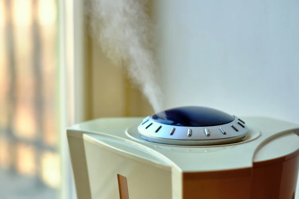 A small humidifier placed on a wooden table, emitting a gentle mist into the air.